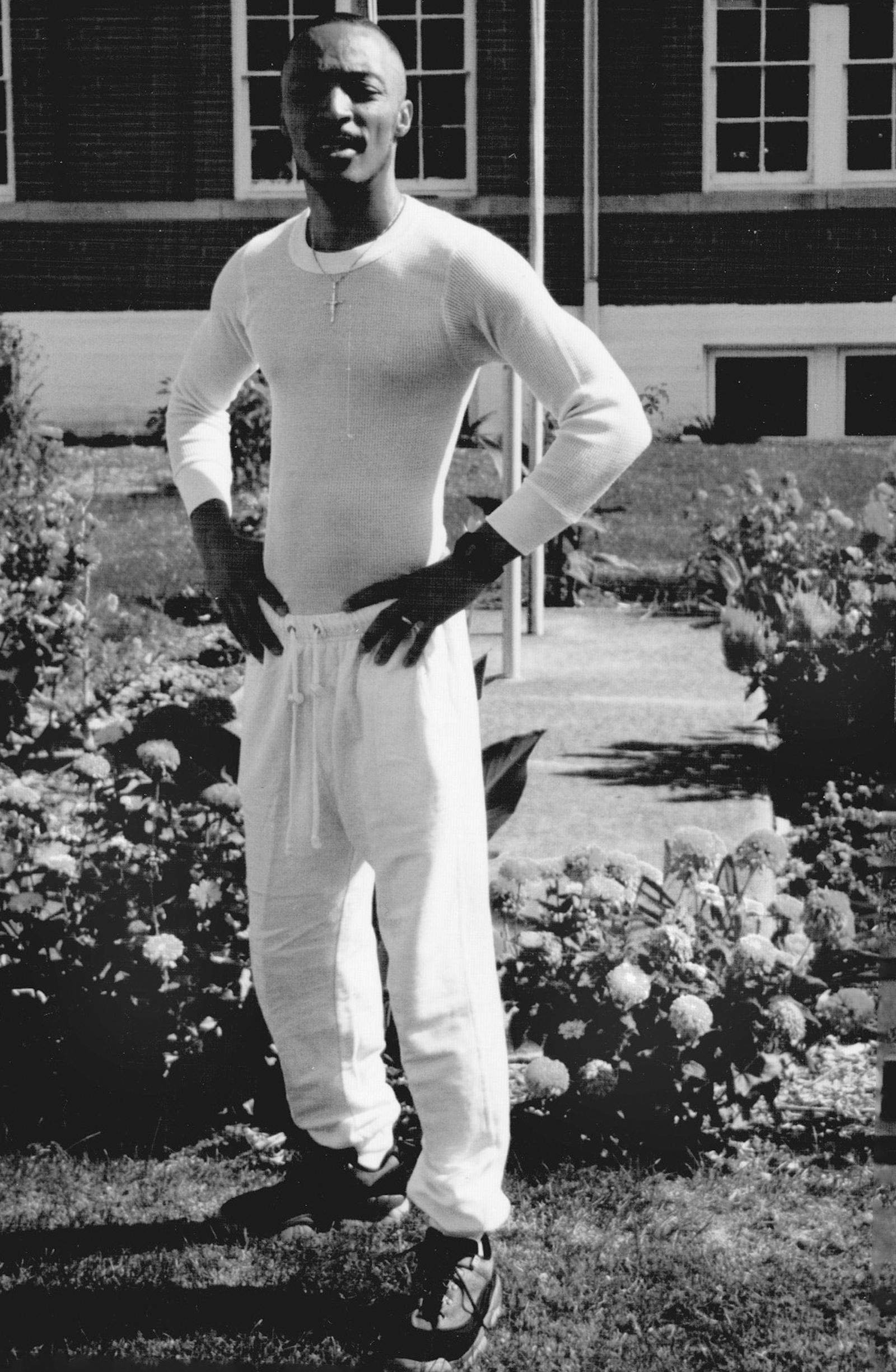 Archie Floyd in a white shirt, standing outside a brick building